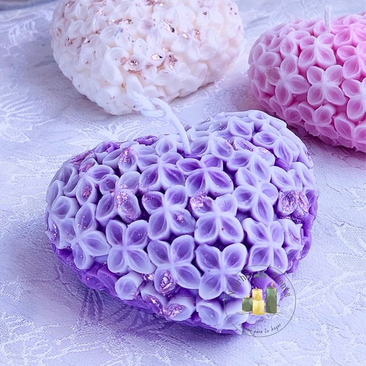 La vela perfecta para los enamorados, encenderá los sentidos con su encanto. Su delicada forma de corazón, decorada con pequeñas flores y chispas de pan de oro, la convierte en el complemento perfecto de veladas&nbsp;mágicas y románticas.

Puedes personalizarla en el color que prefieras, con o sin aroma.